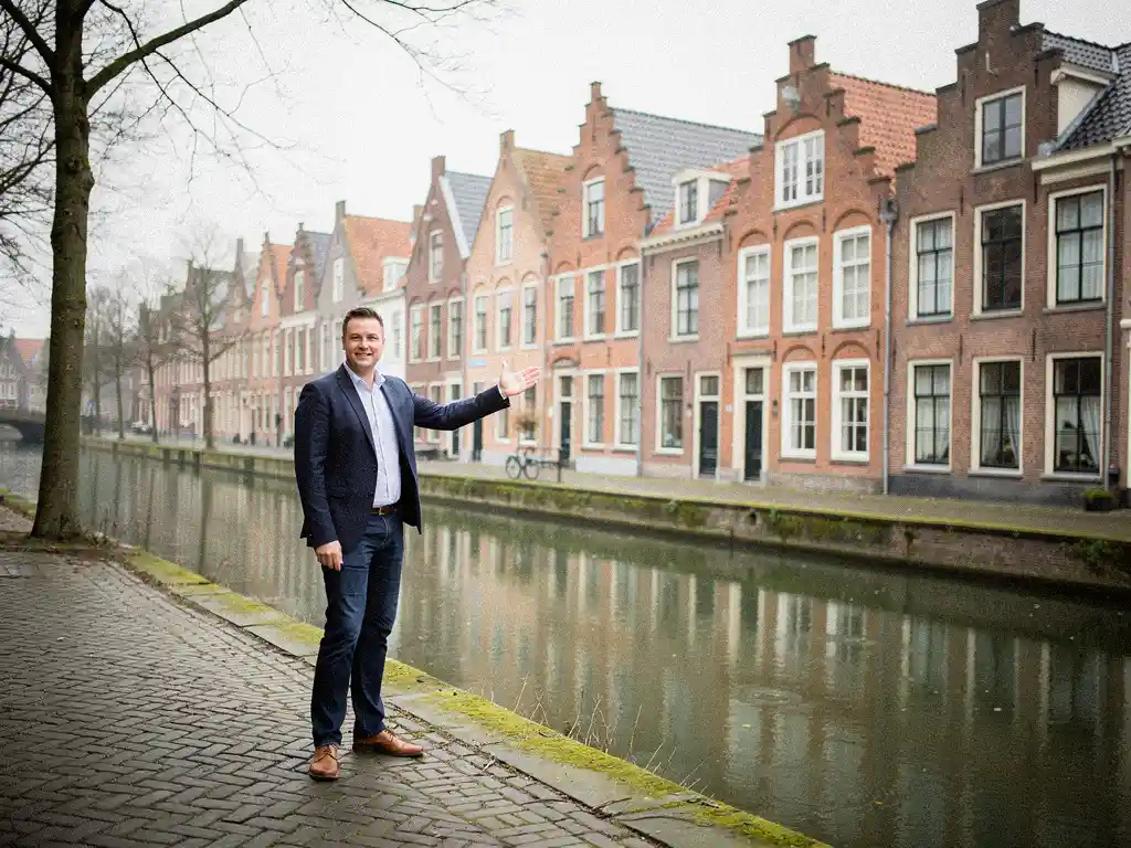 Makelaar in casual kleding wijst naar traditionele roodstenen Goudse grachtenpanden met trapgevels langs een rustige gracht in het vroege voorjaar.